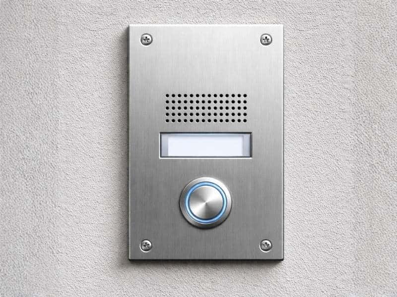 Draadloze intercom met drukknop en speaker op wand, voor toegangscontrole en communicatie bij hek of poort van woning of bedrijf.