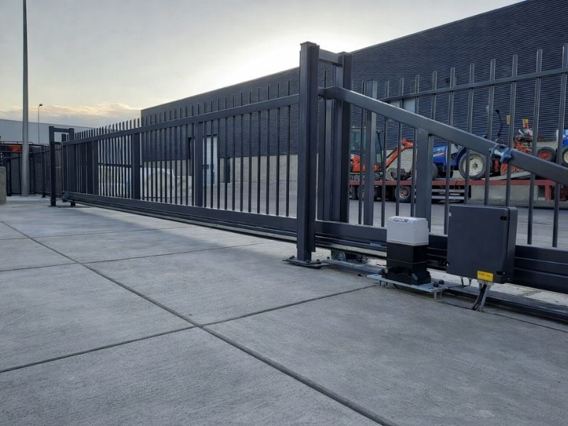 Elektrische schuifpoort van staal bij bedrijfsterrein, voor automatische toegangscontrole en veilige afsluiting met hekwerk