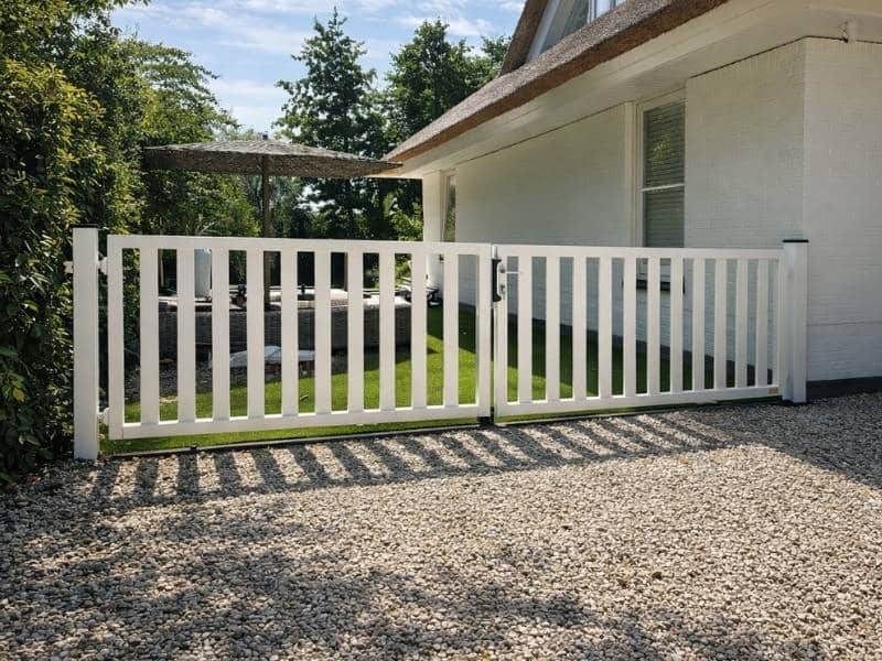 Houten draaipoort in witte afwerking bij woning, voor toegangscontrole en stijlvolle afsluiting van tuin met hekwerk.