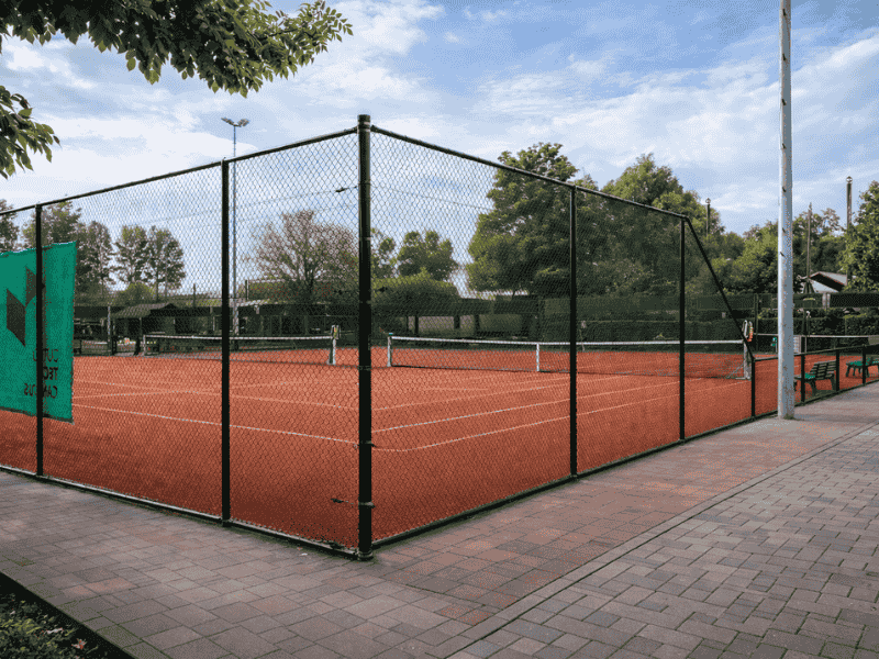 Afrastering rond tennisbaan van gaashekwerk, voor veilige afbakening en toegangscontrole bij tennisbaan.
