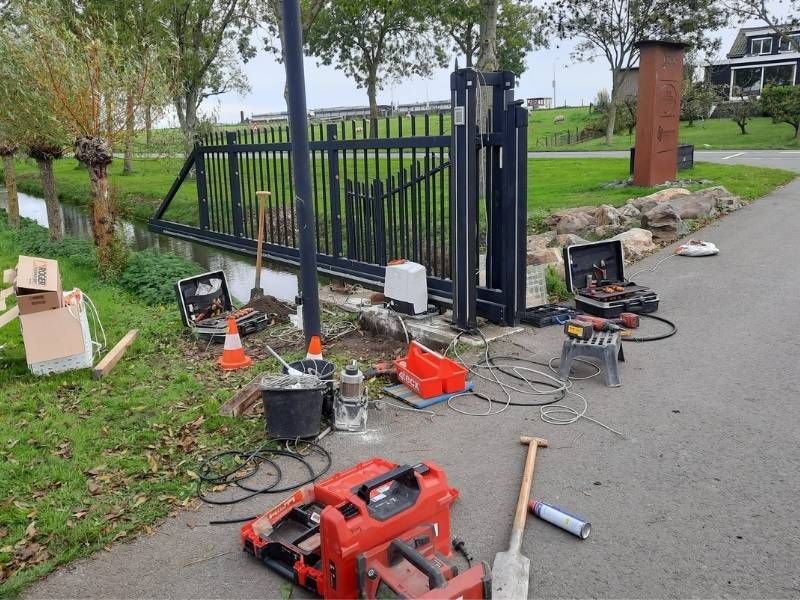 Monteur verhelpt een storing aan een elektrische schuifpoort met poortautomatisering.
