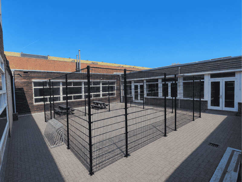 Voetbalkooi met dubbelstaafmat hekwerk en ballenvangconstructie op een schoolplein voor veilig sporten en spelen