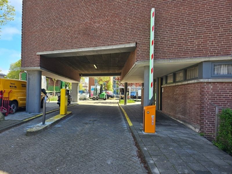 Automatische slagboom bij parkeergarage met verticale boom, voor veilige toegangscontrole en voertuigtoegang.