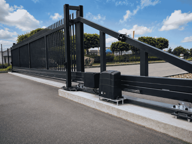 Elektrisch schuifpoort met motor en stalen spijlen, voor automatische toegangscontrole bij bedrijfsterrein.